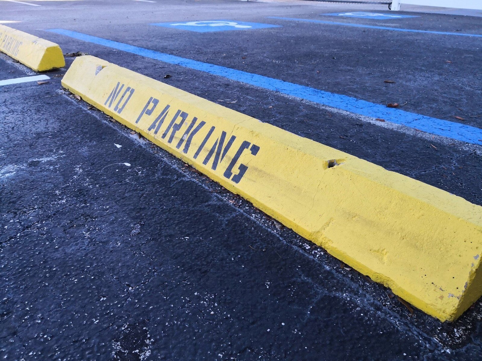 Wheel stop painted yellow with no parking stencil